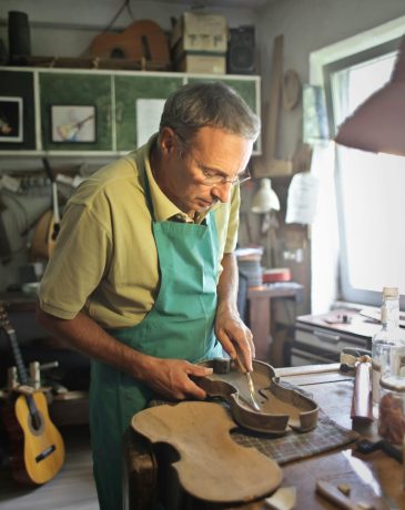 An artisan meticulously crafting a violin in a traditional workshop setting.